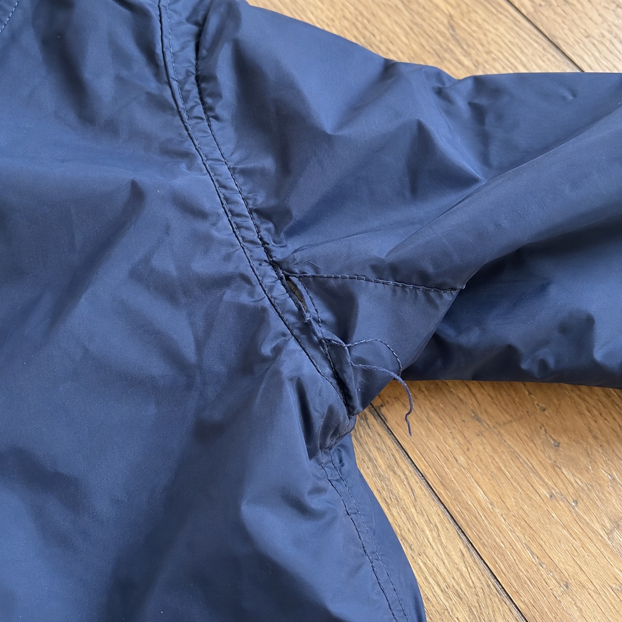 Customer photo of a damaged jacket seam attached to a return case